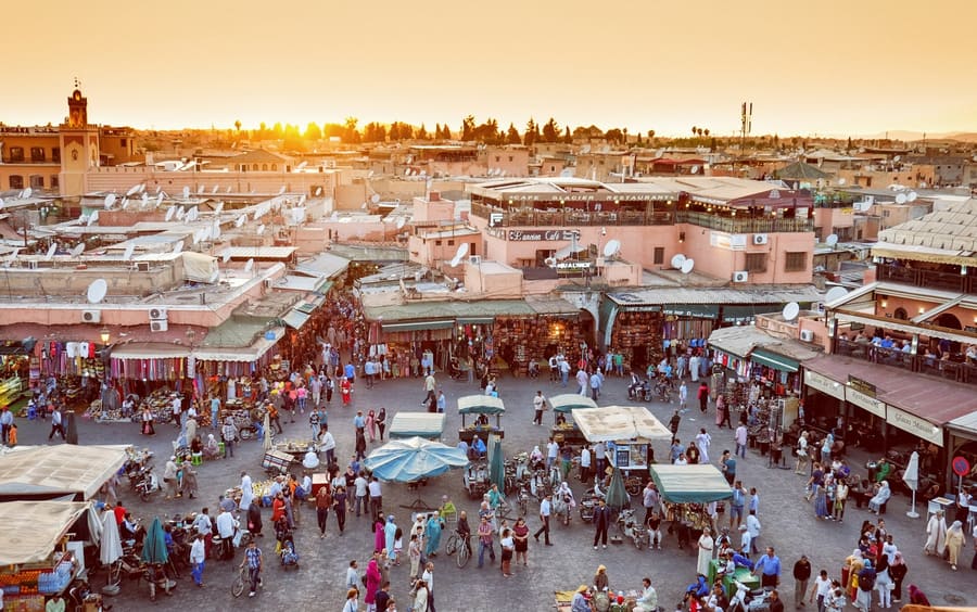 Het plein Jemaa el-Fnaa in Marrakesh bij zonsondergang, met de daken van de medina erachter