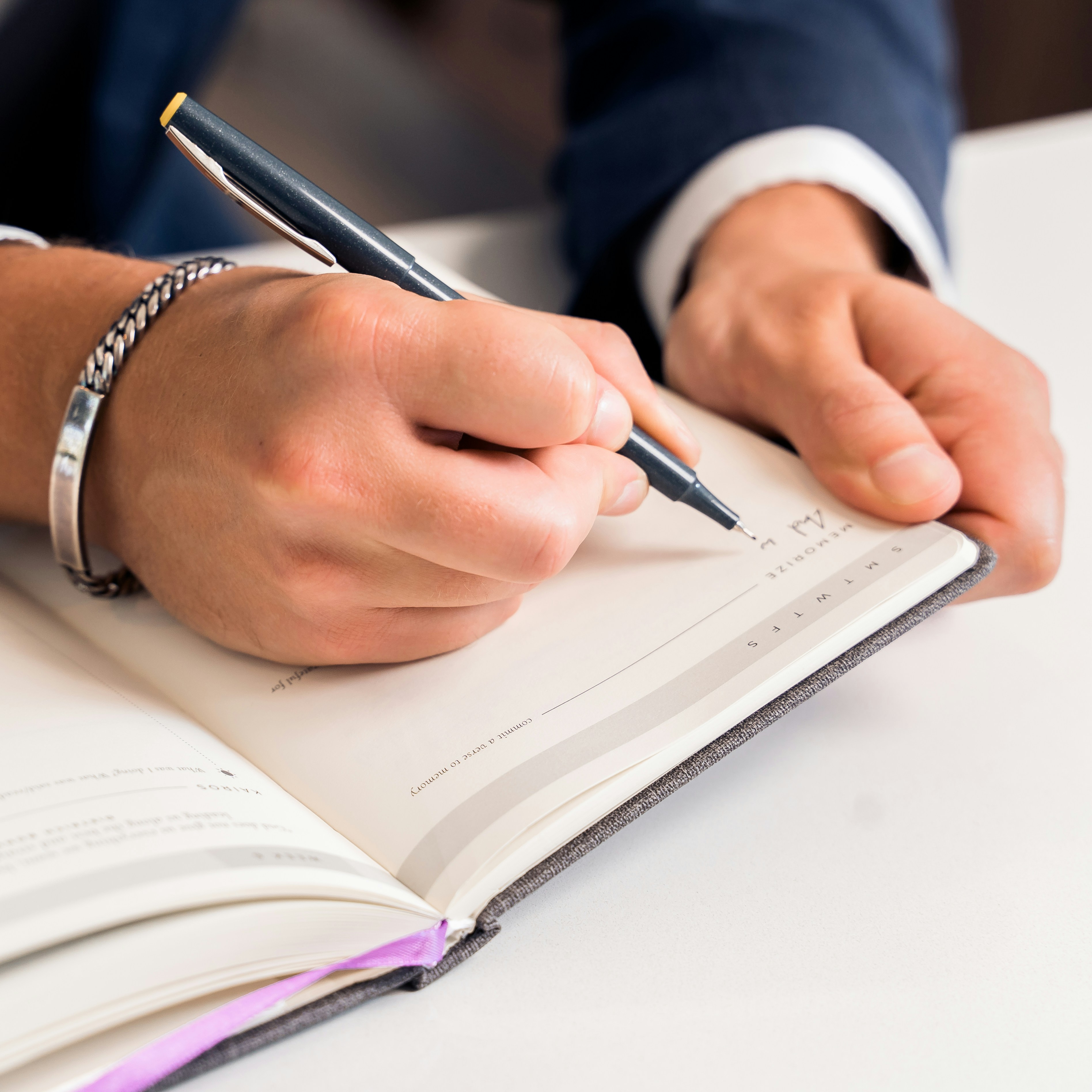 Businessman in suit writing down prayers in his journal.