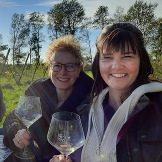 Paula en een vriendin proosten met een glas wijn tijdens de proeverij op Domein Bergen