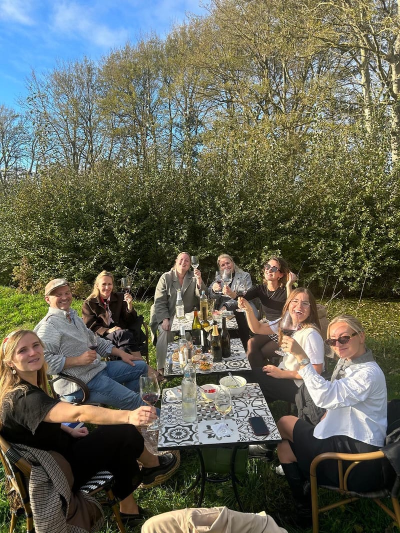 Groep gasten proost aan een lange tafel tussen de wijnranken tijdens de proeverij op Wijndomein Bergen