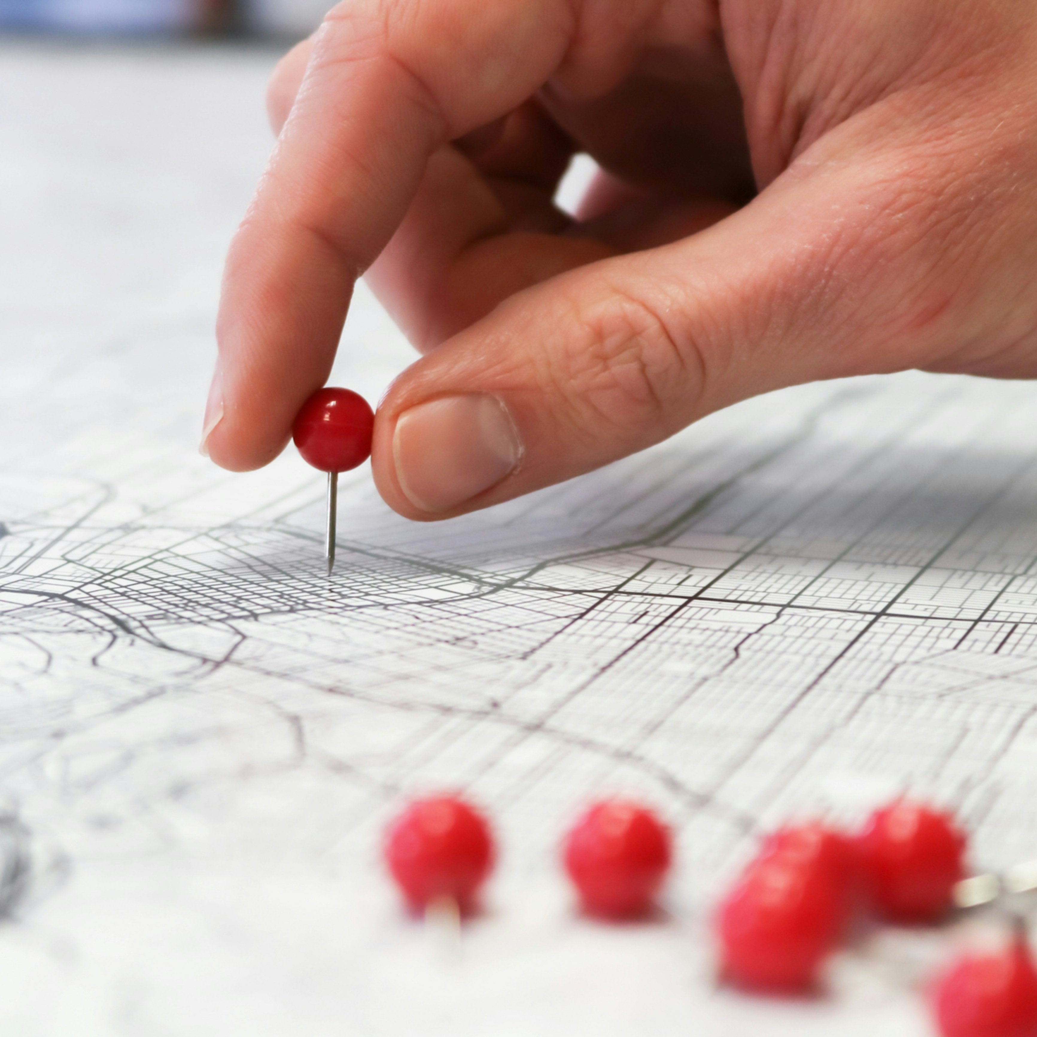 Placing red push pins into city street map.