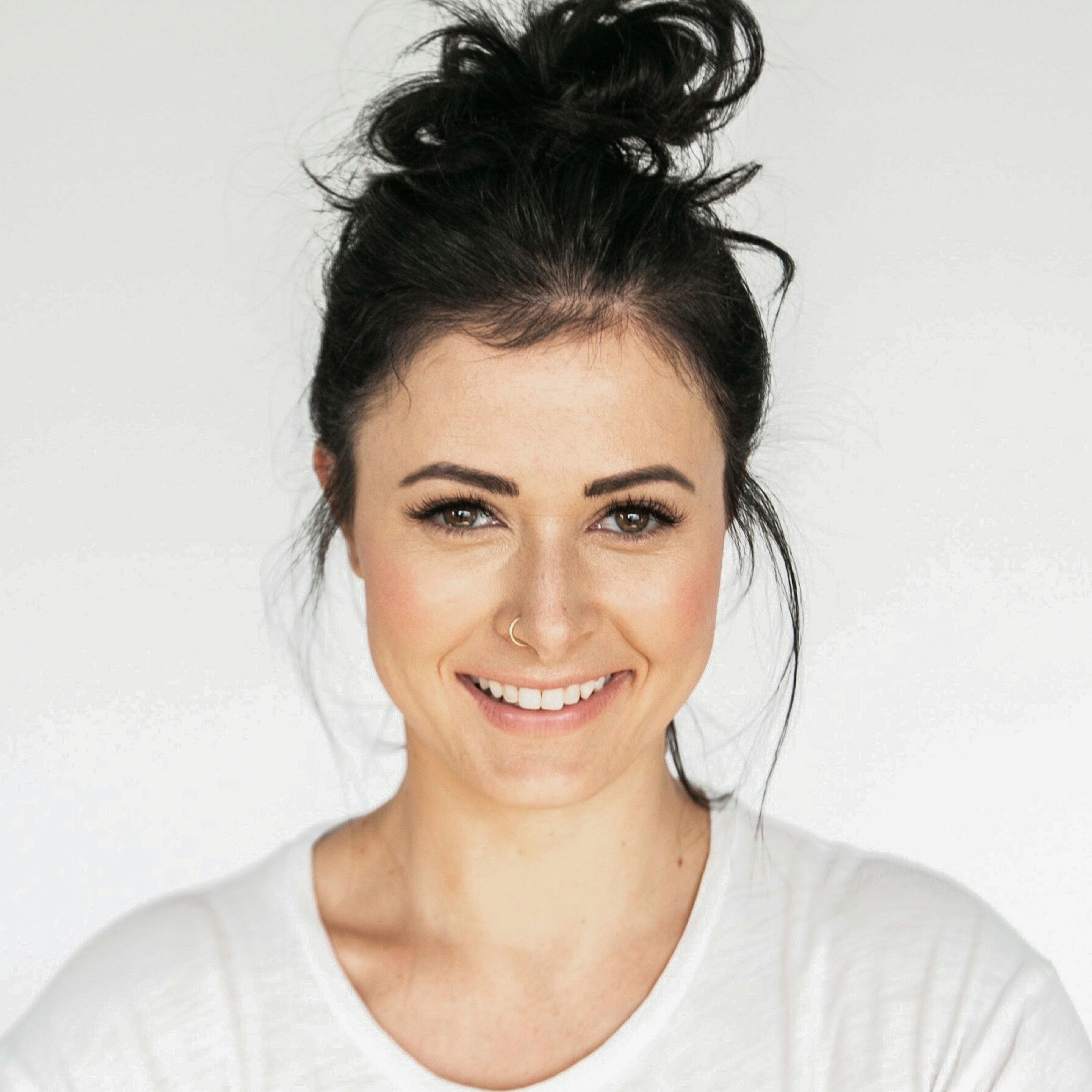 Portrait of a brunette woman smiling with nose ring.