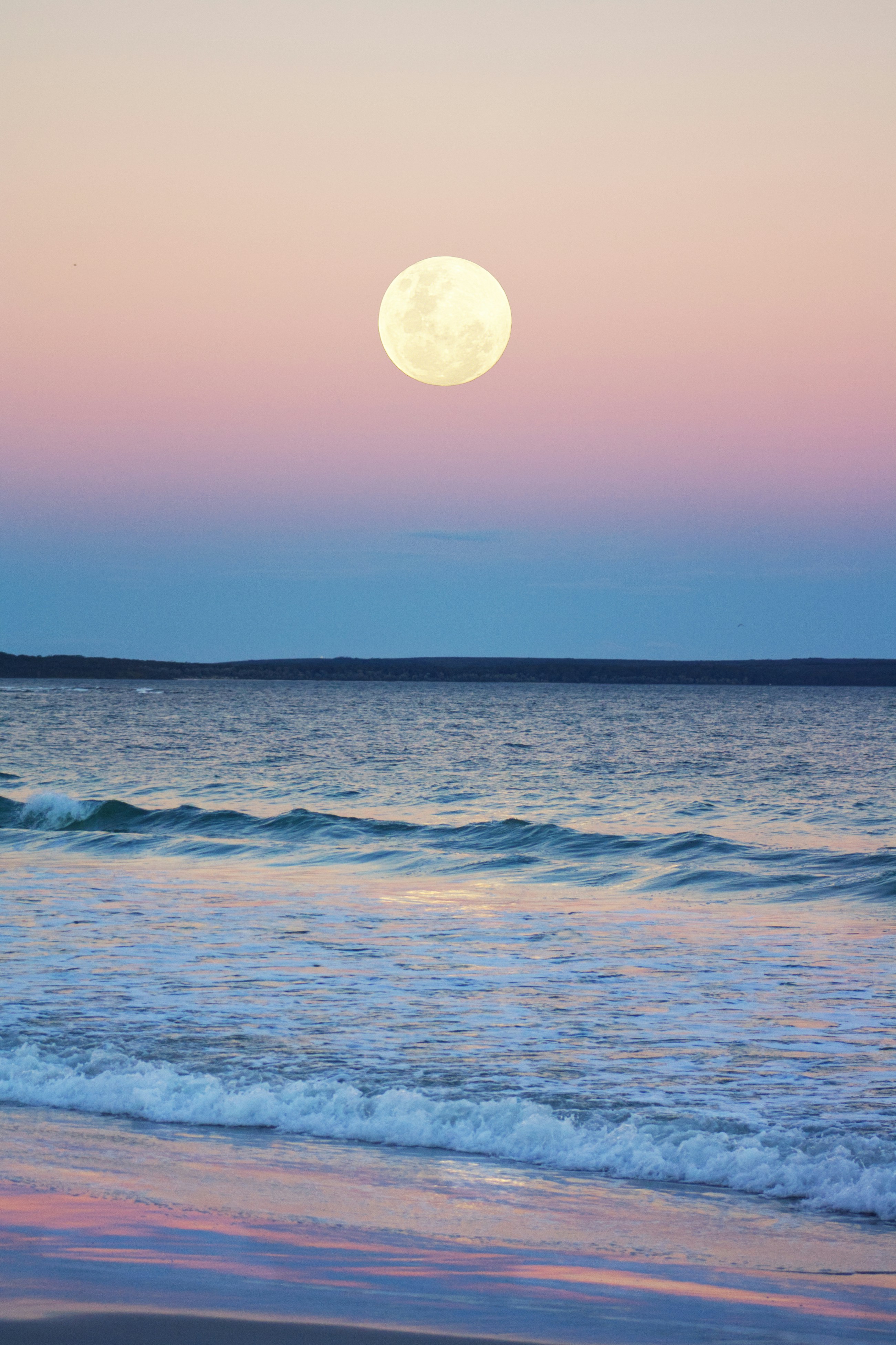 The nearly full moon rising over Jervis Bay, Australia, in blue hour as the last pink leaves the sky.  The famous white sand beaches and crystal clear water catch the light beautifully as it fades.

In this image I have increased saturation, contrast and