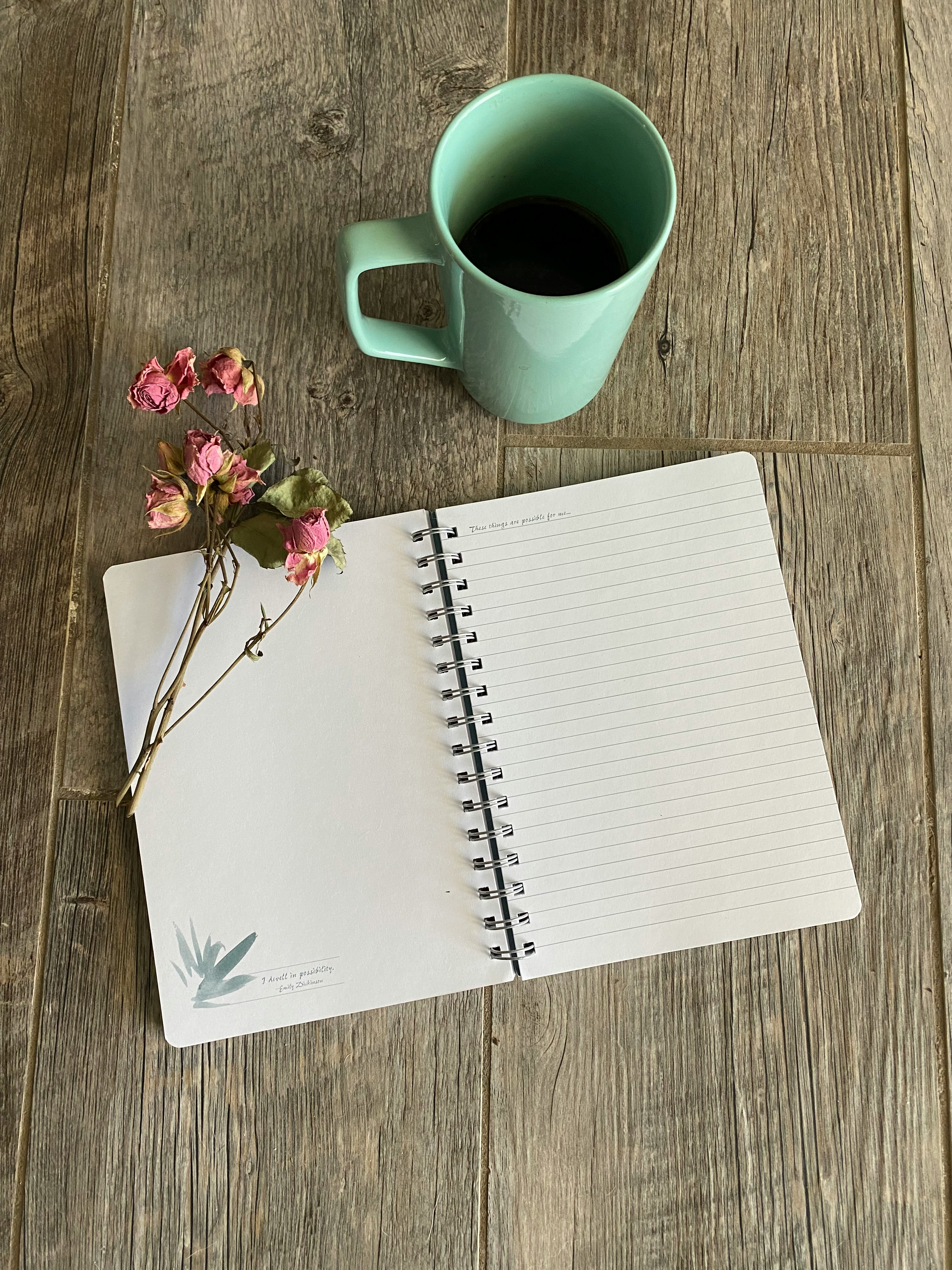 Een journal met bloemen en een tas thee als symbool voor reflectie en vertraging.