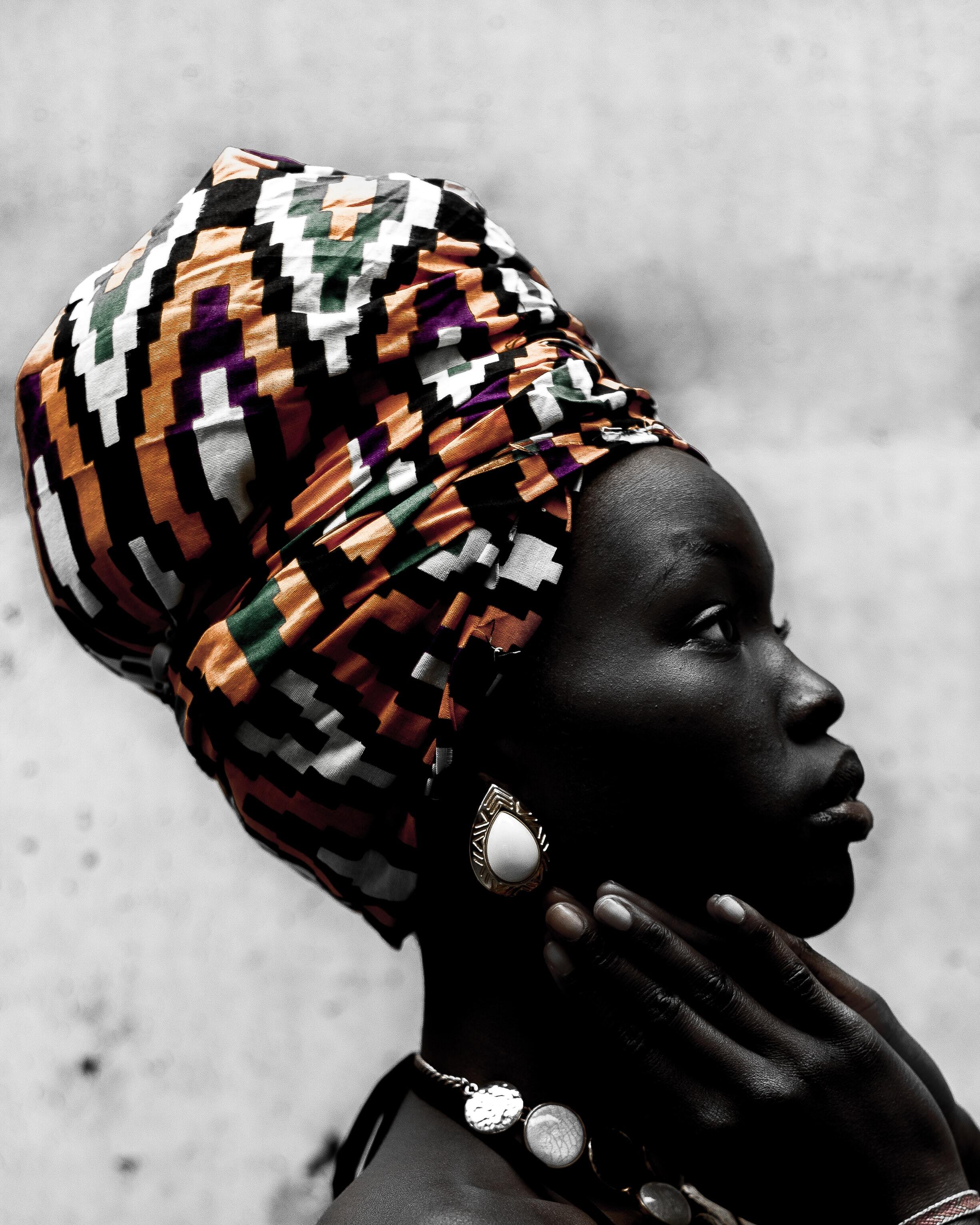 Profiel donkere vrouw met gekleurde hoofddoek in de kleuren, wit, zwart, oranje patroon.