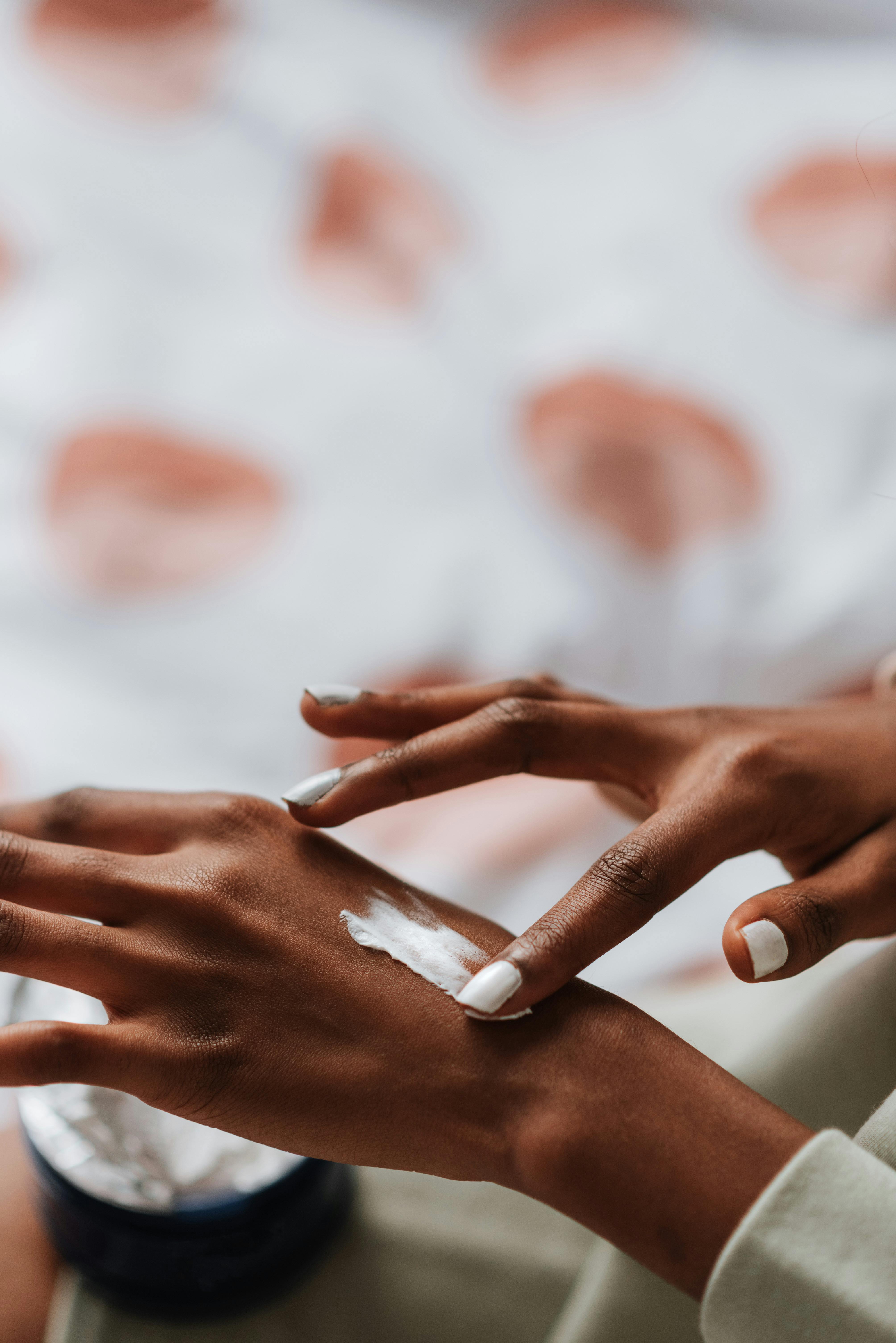 Bruine vrouwen handen, brengt crème aan op een hand. Schoonheidssalon en huidtherapiepraktijk voor de gekleurde MellaCare Rotterdam.