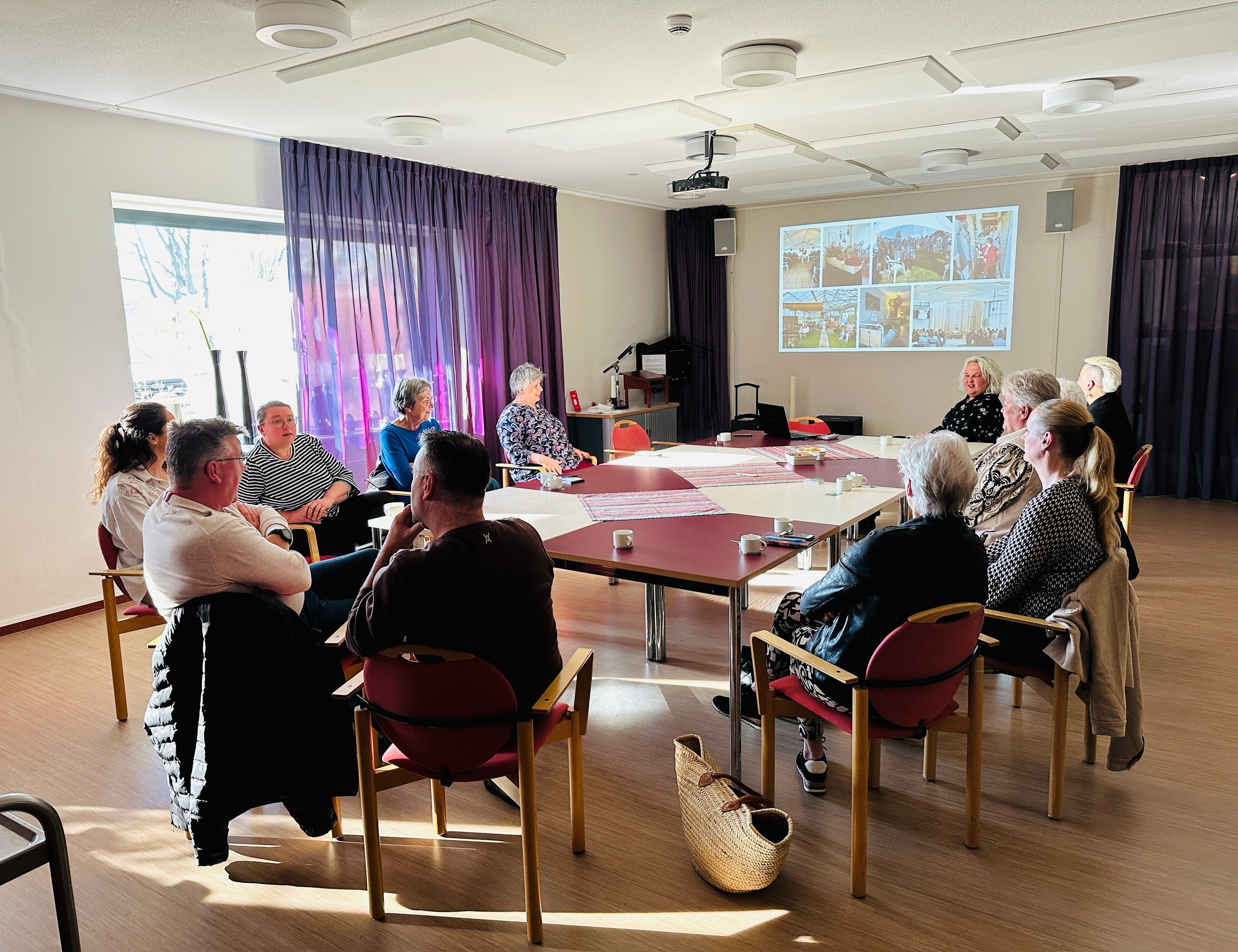 Petra Komdeur tijdens een lezing over afscheid, in gesprek met zorgverleners en naasten in een kringvormige setting.