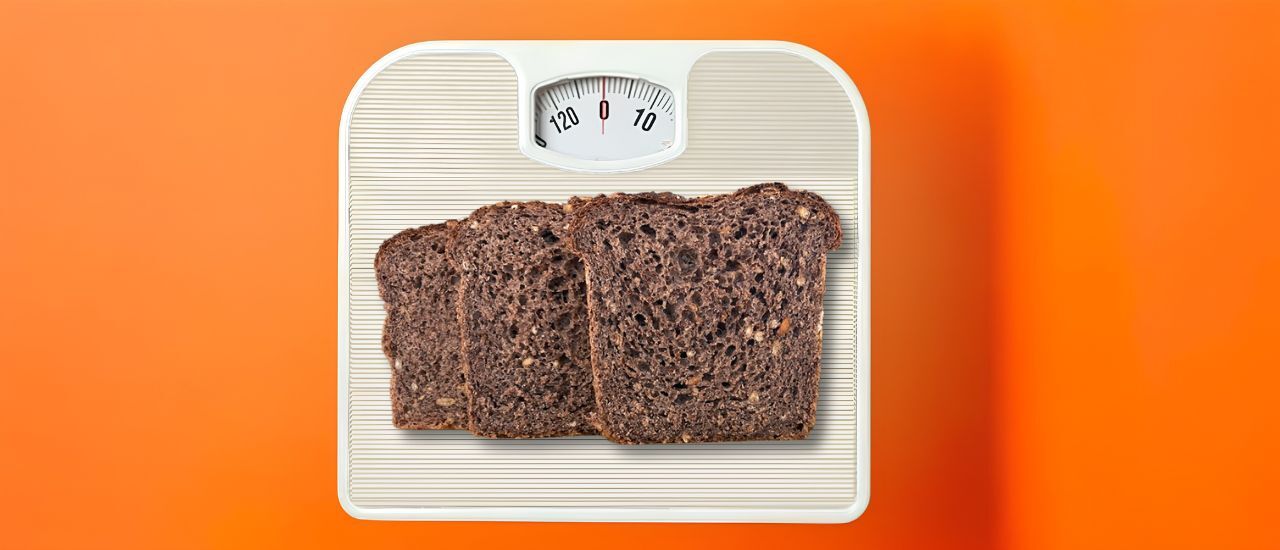 Drie sneden volkorenbrood op een personenweegschaal die op nul staat: word je dik van brood?