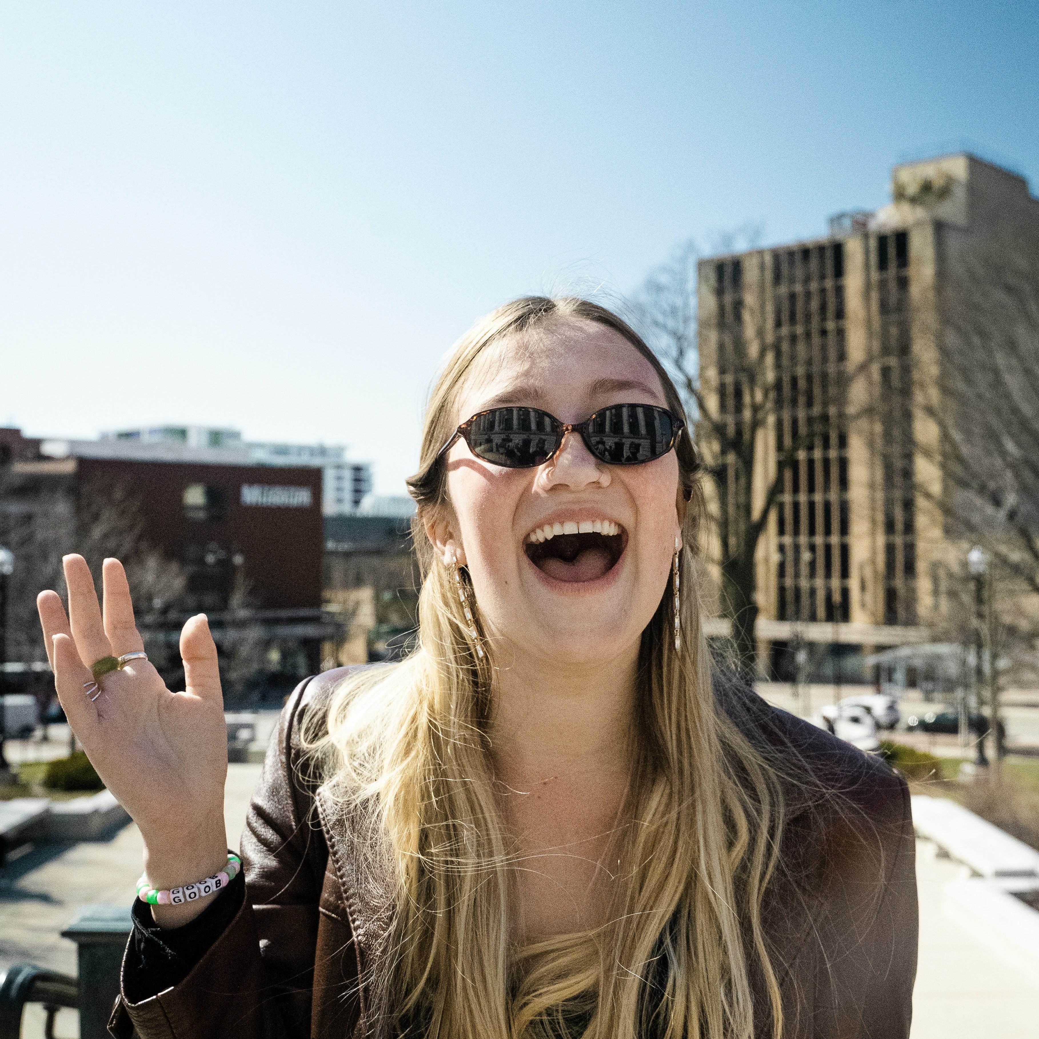 Girl smiling in sunglasses standing in front of Madison, Wisconsin