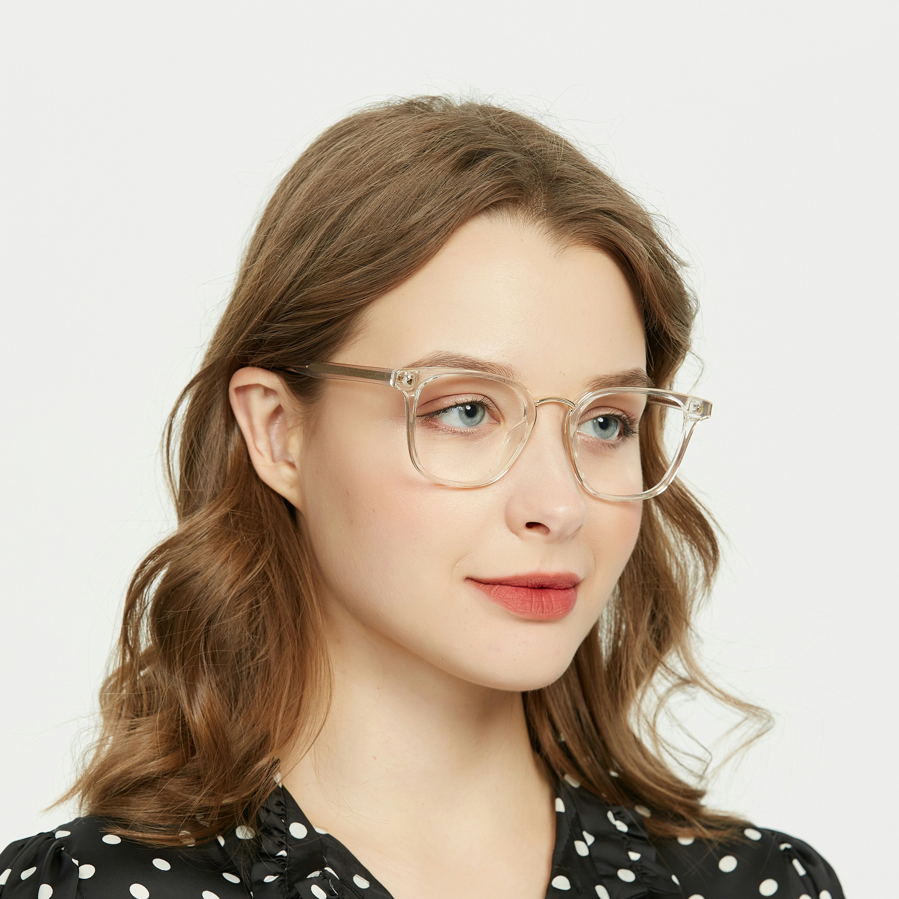 Sophisticated woman dons clear glasses, accentuating her features. The frames harmonize with her polka-dot blouse, exuding classic elegance.