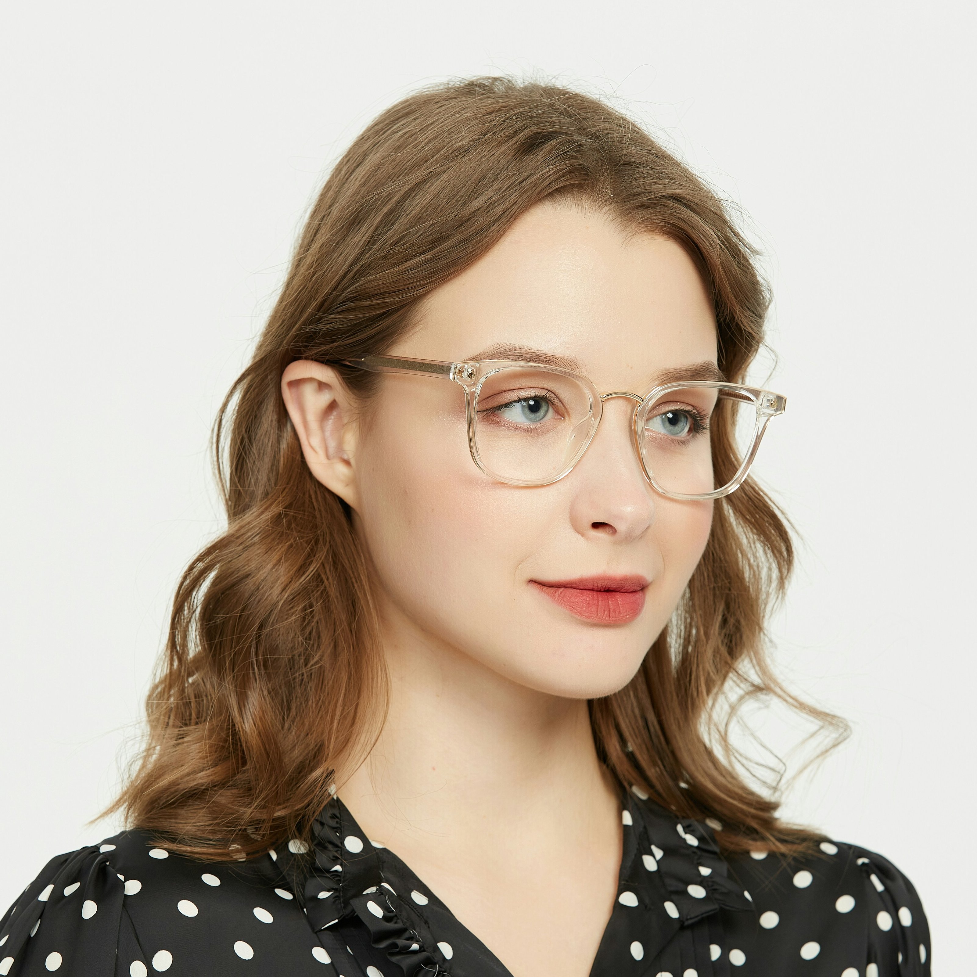 Sophisticated woman dons clear glasses, accentuating her features. The frames harmonize with her polka-dot blouse, exuding classic elegance.