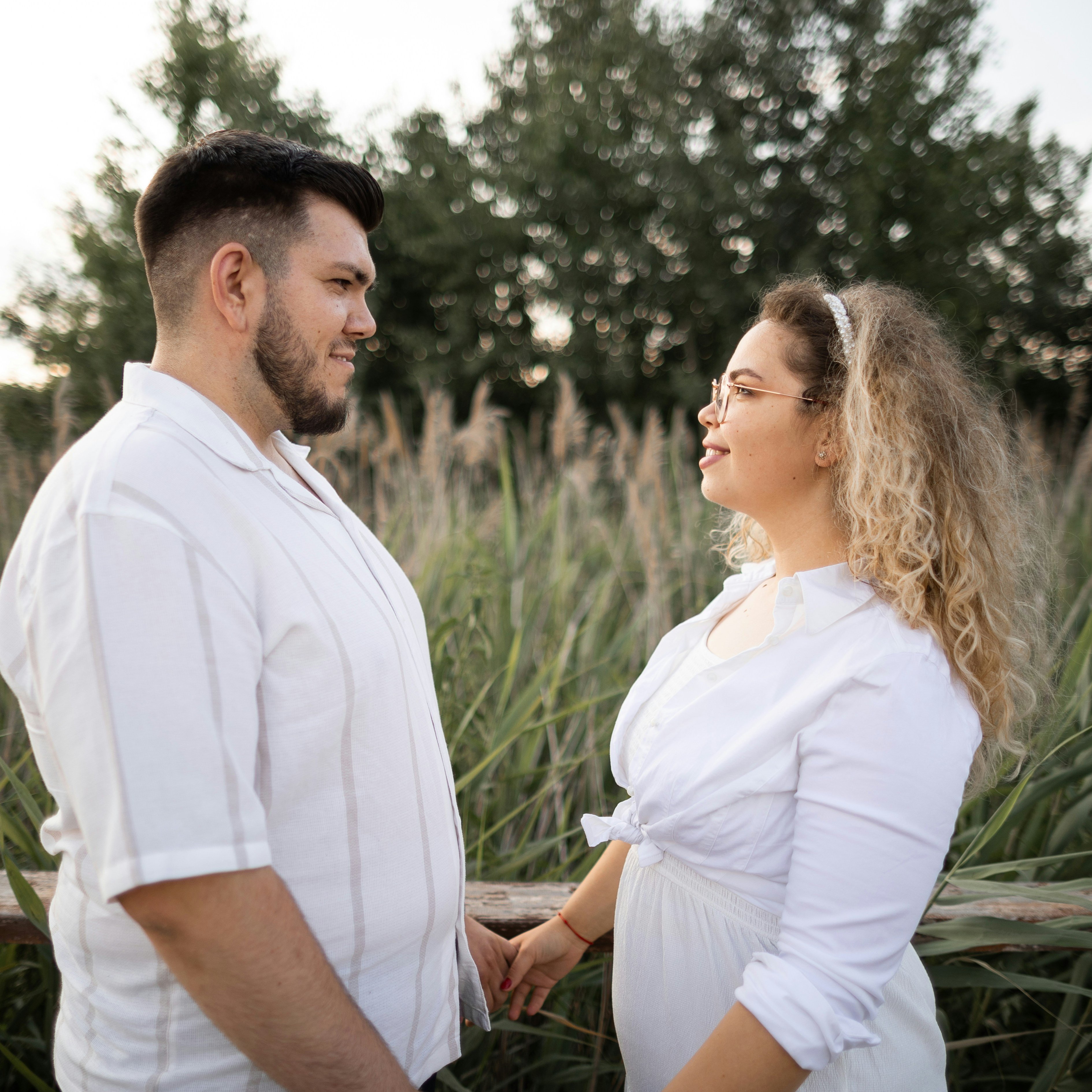Man and his fiancé holding hands, looking at each other and smiling.