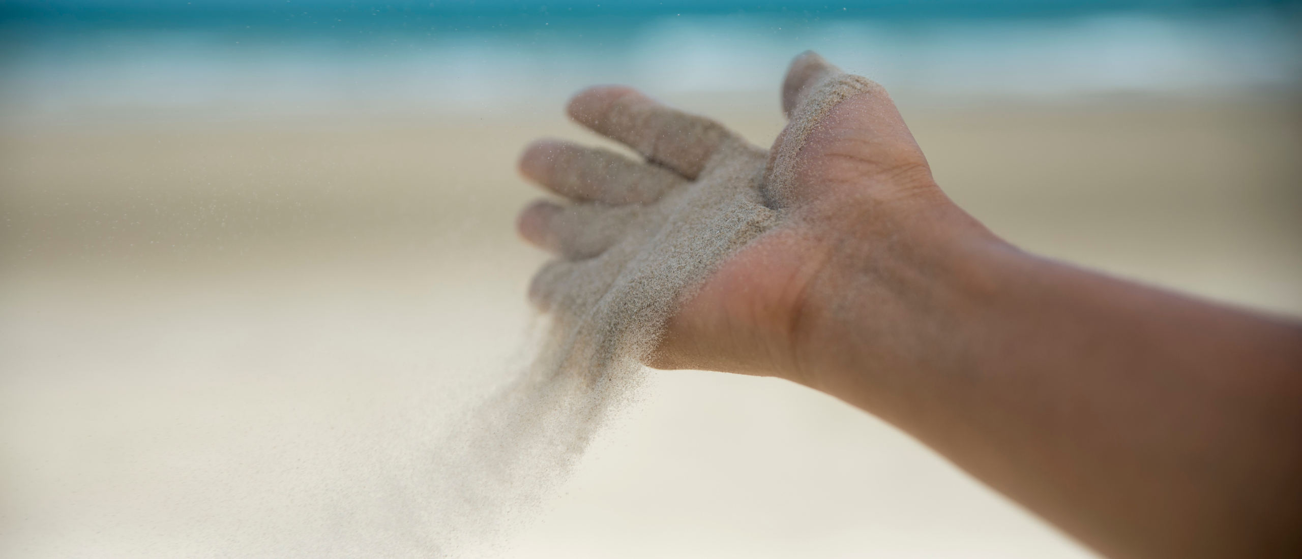 Een open hand waar zand uitwaait omdat de hand het zand niet meer vasthoudt. Symbool voor het loslaten van de controle.