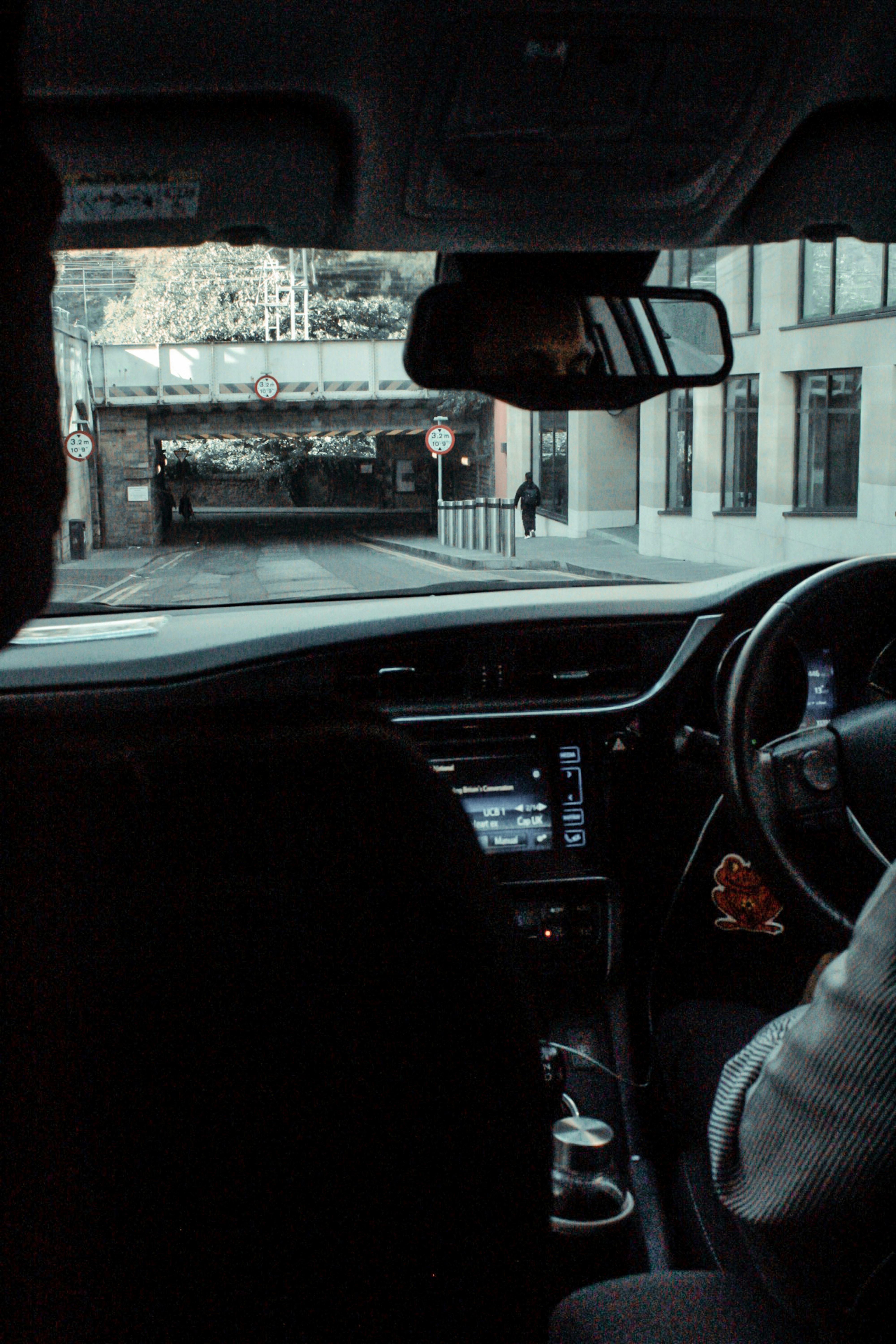 In car, first-person view of driving through city towards bridge and buildings.