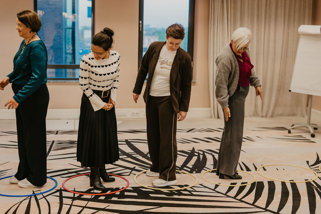 Vier vrouwen tijdens een assertiviteitstraining staan elk in hun eigen cirkel, symbool voor persoonlijke ruimte, grenzen en zelfvertrouwen