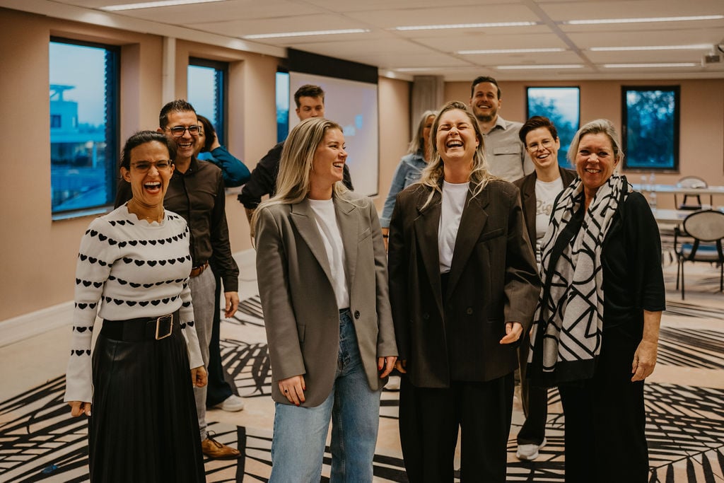 Een groep deelnemers barst in lachen uit tijdens een training, symbool voor de energieke, laagdrempelige en verbindende sfeer van de Proeverij