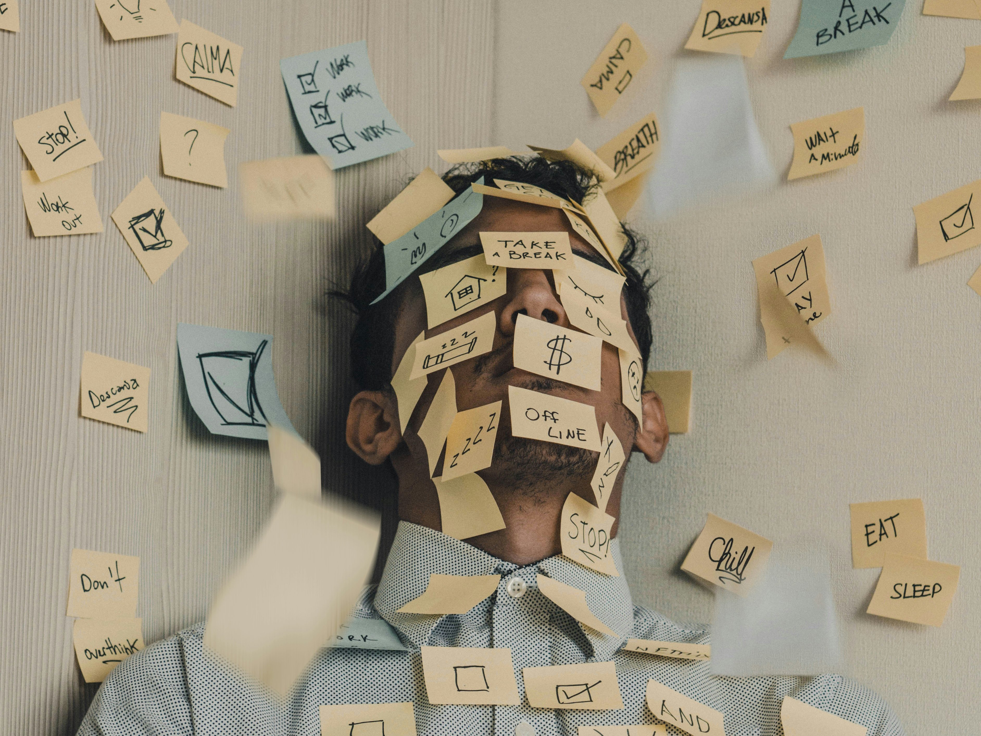 Young man covered in sticky notes, work overload