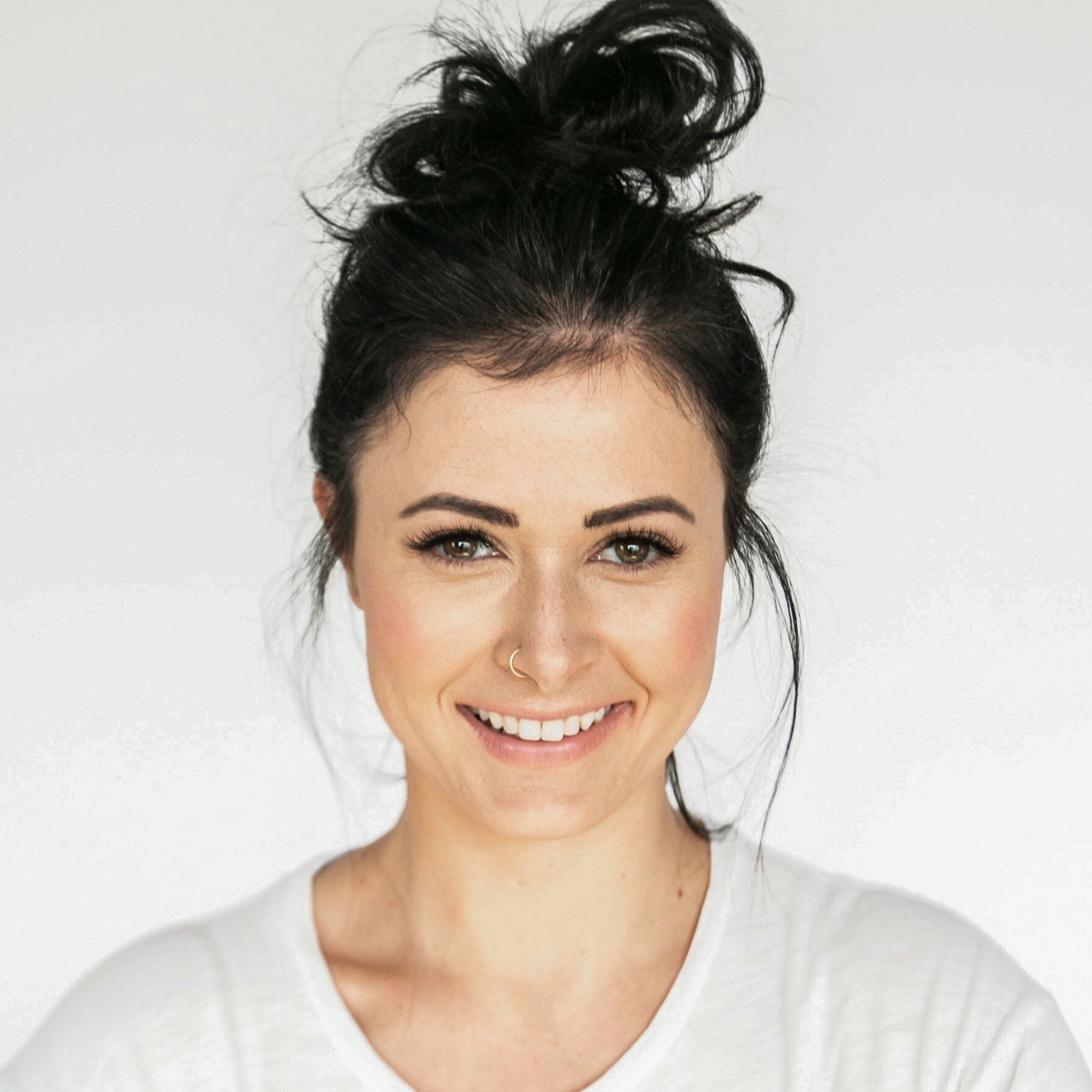 Portrait of a brunette woman smiling with nose ring.