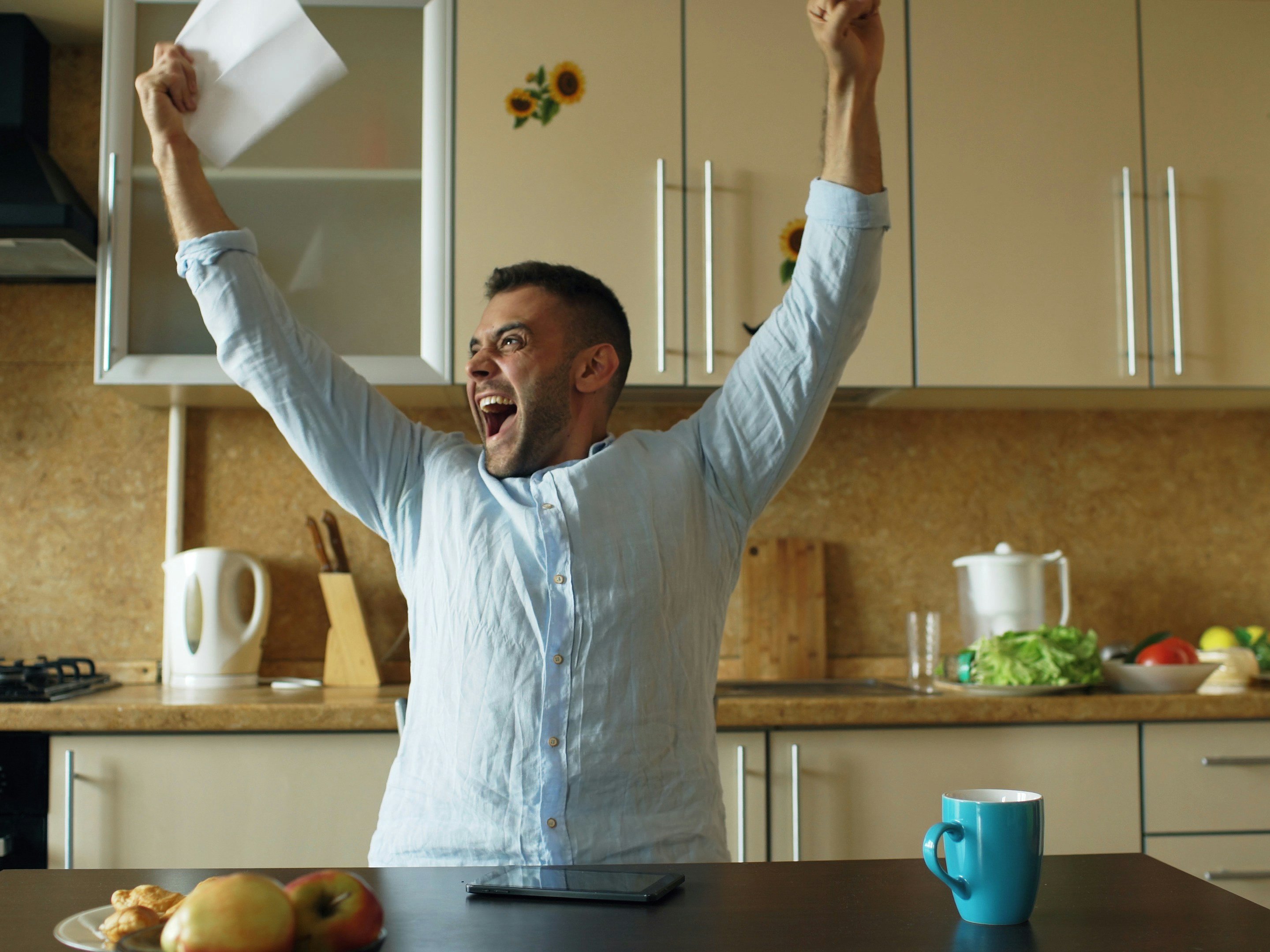 Handsome man recieve good news reading letter in the kitchen while have breakfast at home