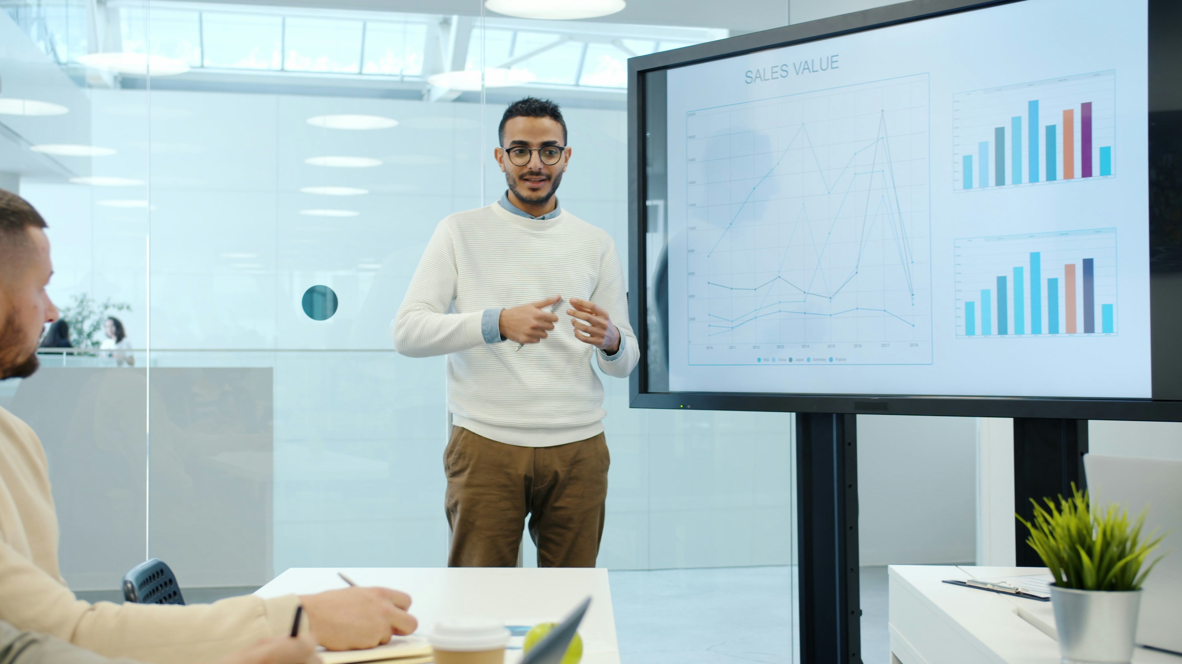 Arab man discussing marketing research with group of people in office using interactive board for presentation talking and gesturing indoors.