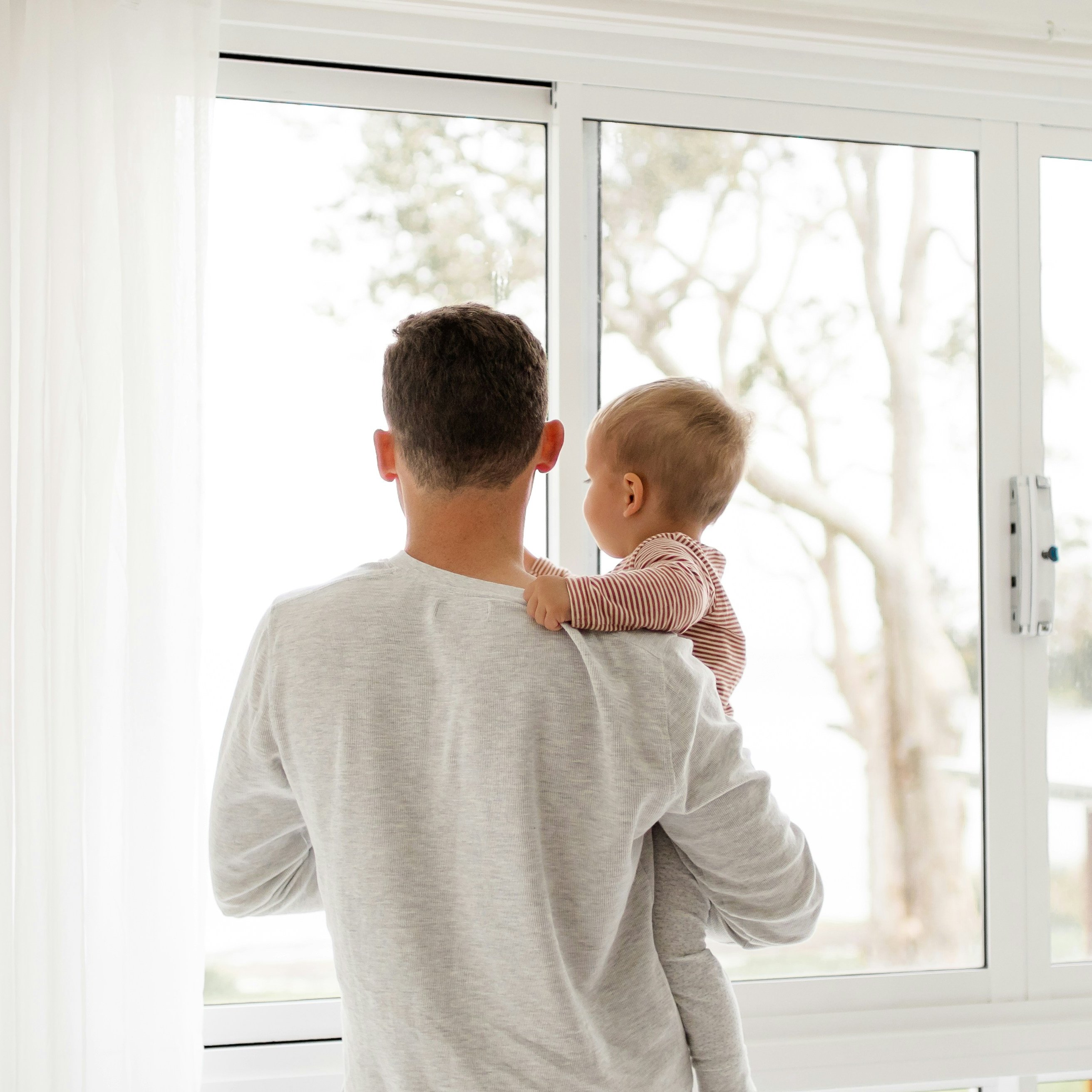 Father holding child looking out a window