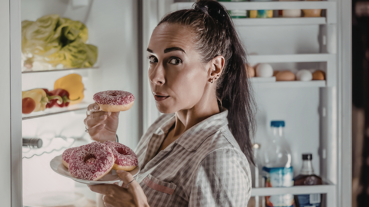 Vrouw staat 's avonds voor open koelkast — herkenbaar beeld van avondsnacken bij overgewicht 50 plus