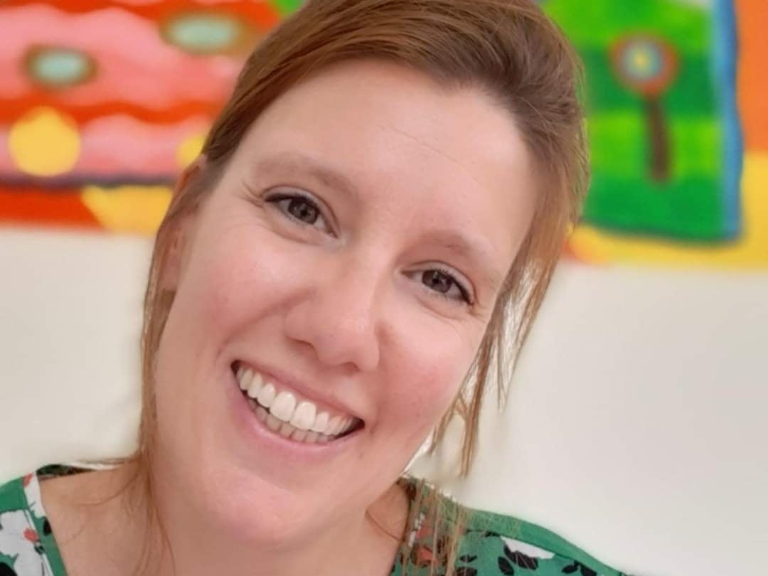 Foto van Joyce lachend voor een kleurrijk schilderij.