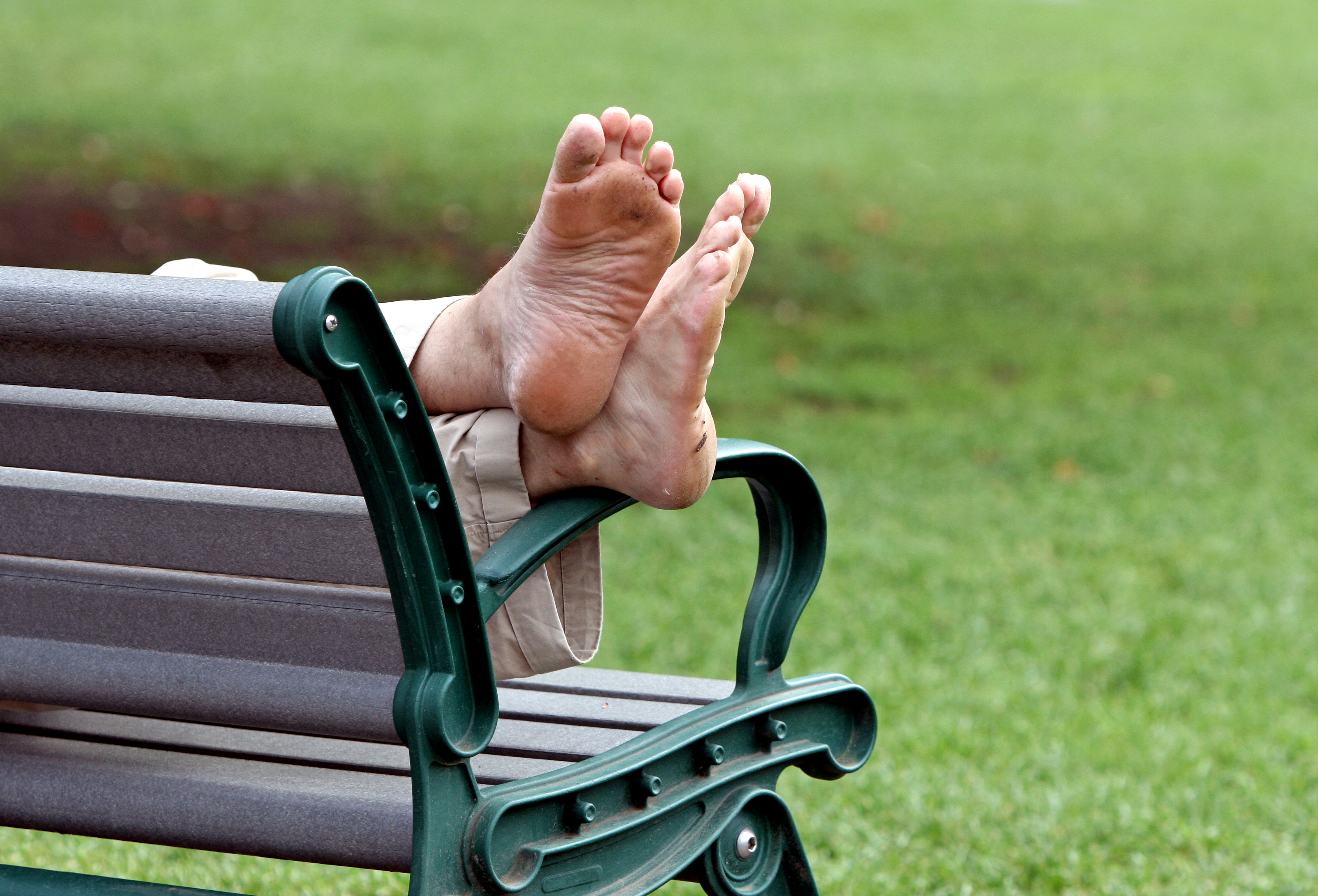 "Foot Rest" --- A man takes a rest on a park bench with his feet up.