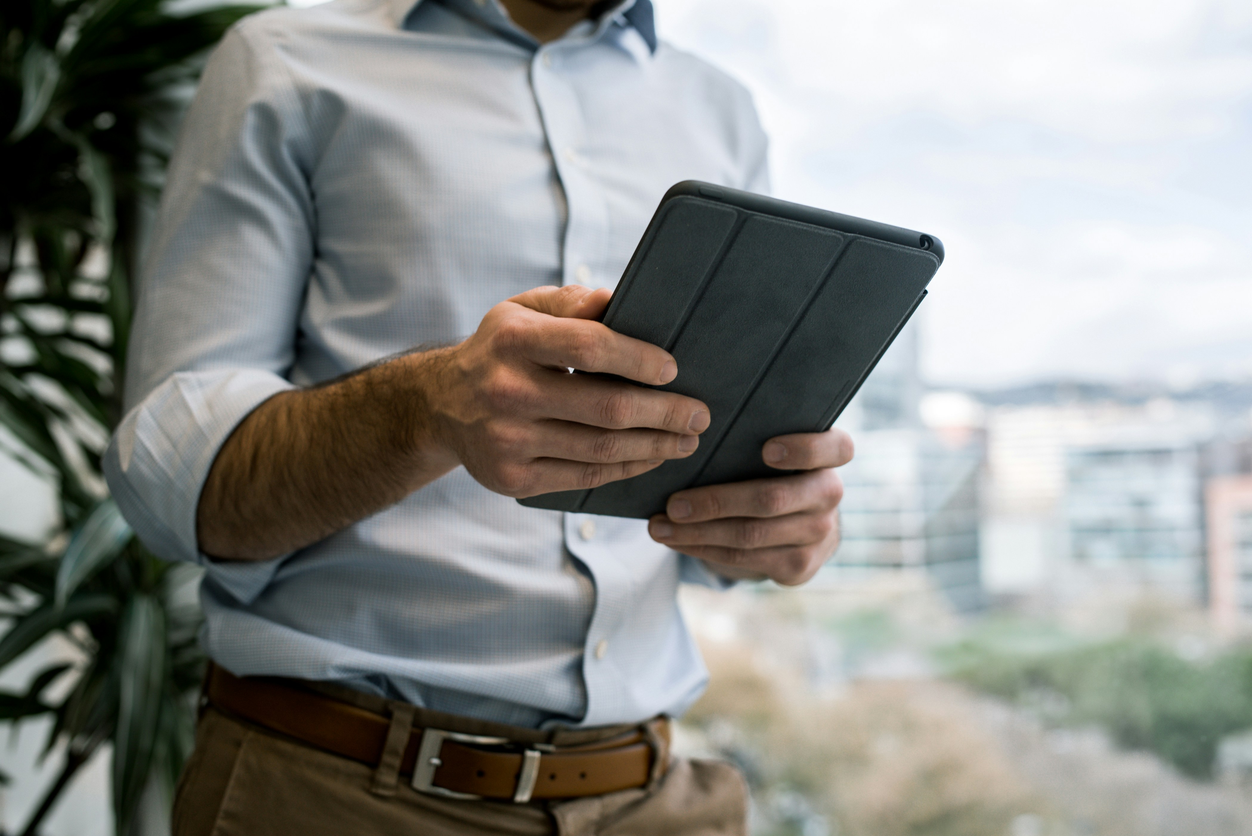 Man looks at iPad while working near the window of a high-rise building. - www.chromaluts.shop