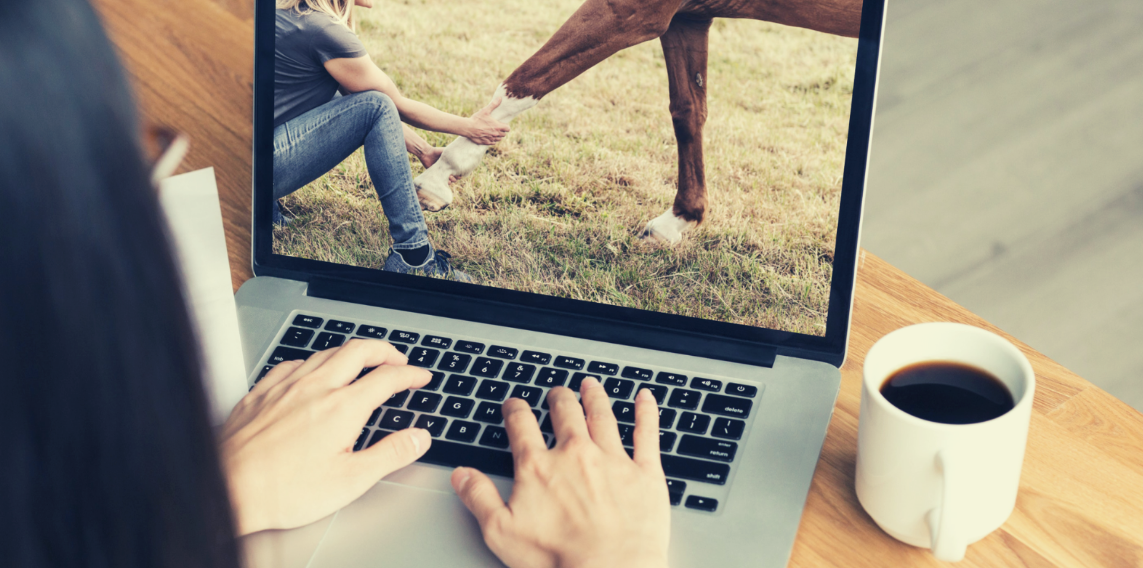 Vrouw volgt een online module over paardenbehandeling met praktijkvideo op laptop met koffietas ernaast