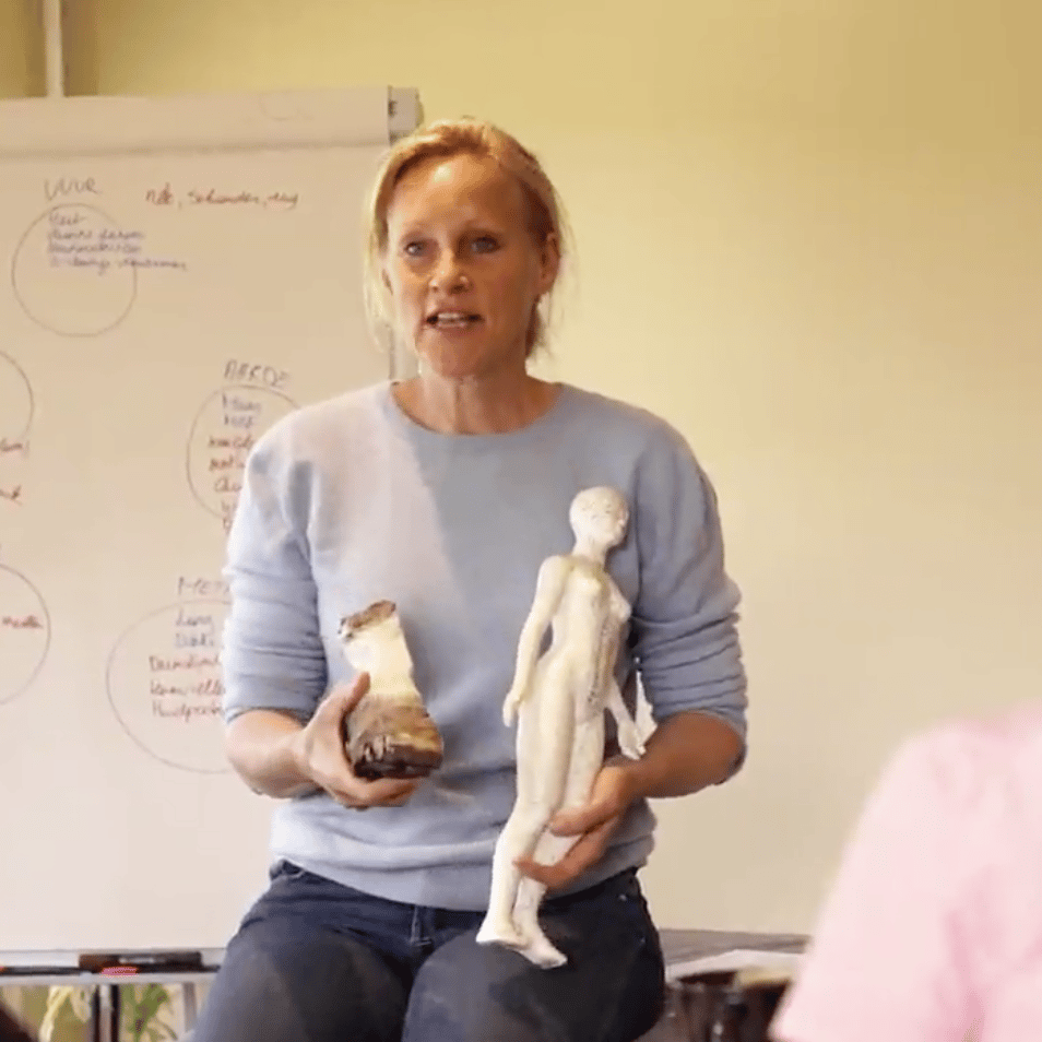 Evy, een blonde vrouw houdt een hoef van een paard vast en een pop met meridianen op getekend